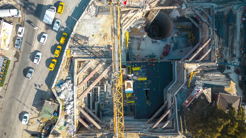 4K hyperlapse time-lapse of under construction site, crane, and car traffic transportation in city downtown. Drone aerial top view. Industrial business or civil engineering technology concept