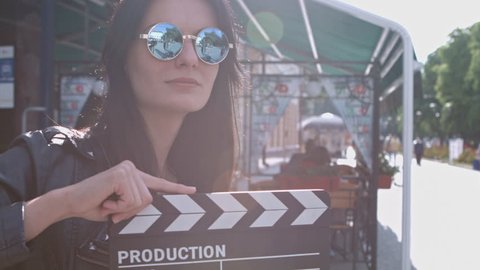 Beautiful girl with a clapperboard on the streets