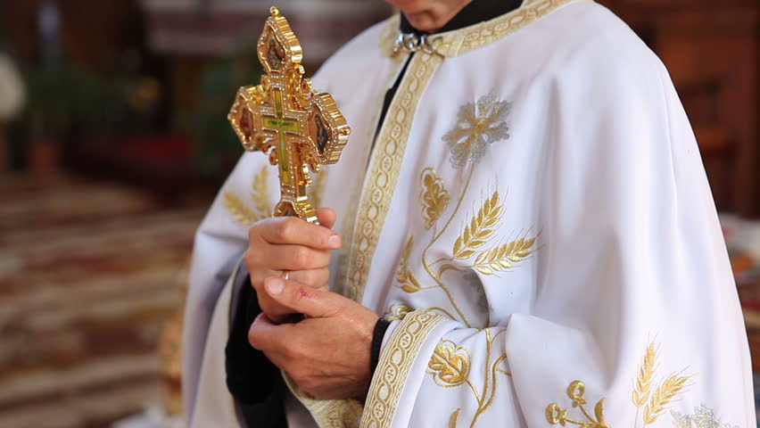 An Orthodox priest in a cassock holds a metal cross in his hands. The pastor preaches while standing in front of the congregation. Church liturgy. | Shutterstock HD Video #1098791367