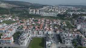 orbit aerial view of red roofs city from above and with some green fields close by, drone video footage. Portugal