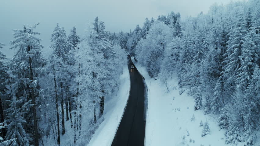 Epic view of car drive on empty road in snowy forest wonderland. Cinematic shot of white freezing trees in cold winter season. Road trip in magical winding mountains. | Shutterstock HD Video #1098796267