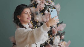 A young woman records a video for social media against Christmas tree