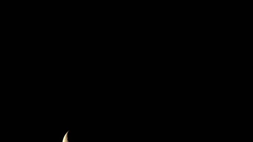 Time lapse of rising crescent moon on black cloudless background.