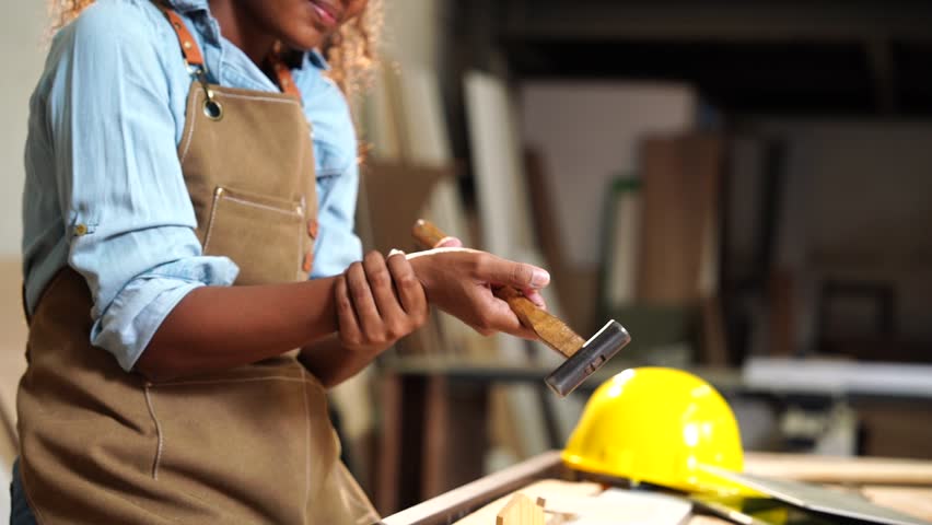 African American female carpenter with wrist pain during handmade workshop at home.