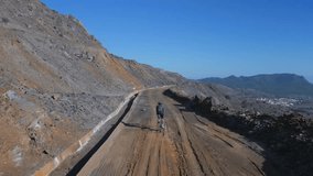 Camera follows fit male cyclist athlete riding on a scenery mountain gravel road, a lone riding sportsman. Healthy outdoor lifestyle for cycling athletes. Cardio training motivation video.