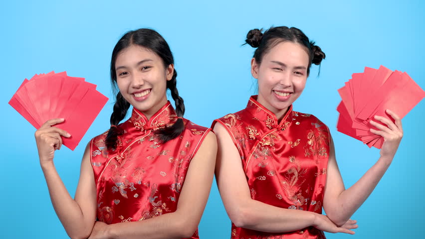 Asian pretty women in traditional red costume clothes happy show many ungpao in Chinese culture, young working girls receive surprise bonus or reward in red envelops, women shopping lifestyles concept