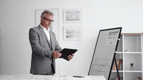 Digital business. Virtual audit. Information technology. Confident smart senior entrepreneur man using tablet for statistics accounting at light modern office interior. - Powered by Shutterstock - Get 15% off with code: PIKWIZARD15