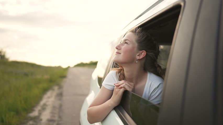 Child in car window. Family car trip. Child hair in wind. Girl looks out of car window. Happy child travel with his family. Girl stretches out his hand to wind. Happy family travel concept by car Royalty-Free Stock Footage #1098814621