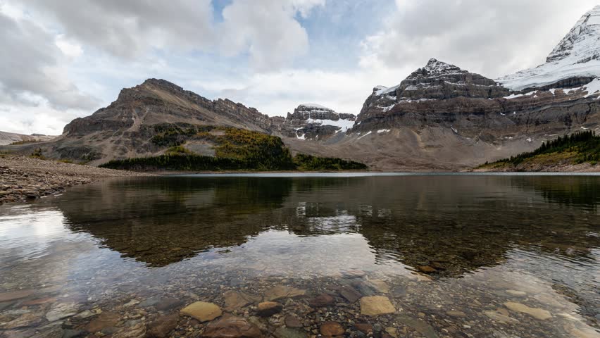 Time lapse of Mount Assiniboine famous with rocky mountains and blue sky reflection on Lake Magog at Assiniboine provincial park, BC, Canada