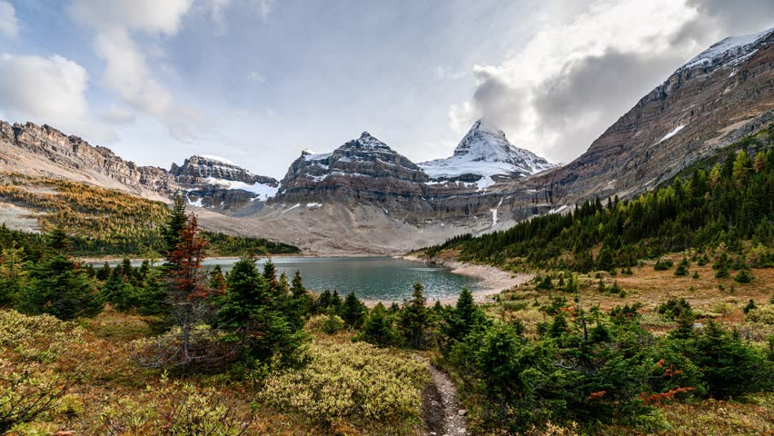 Time lapse of Mount Assiniboine famous with blue sky in autumn forest reflection on Lake Magog at Assiniboine provincial park, BC, Canada