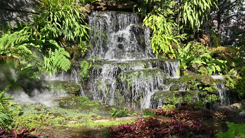 Water flowing from large artificial waterfall in ornamental garden.