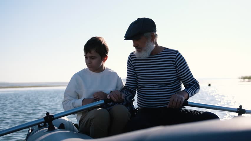 Portrait of an elder grandfather and grandson sitting in a boat on a fishing trip Royalty-Free Stock Footage #1098820631