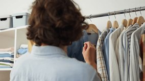 Looking for clothes on a hanger clothes rack girl looking for fashion clothes in a warehouse, Fashion clothes on wooden hangers in a store, wardrobe garments in the house clothing with things
