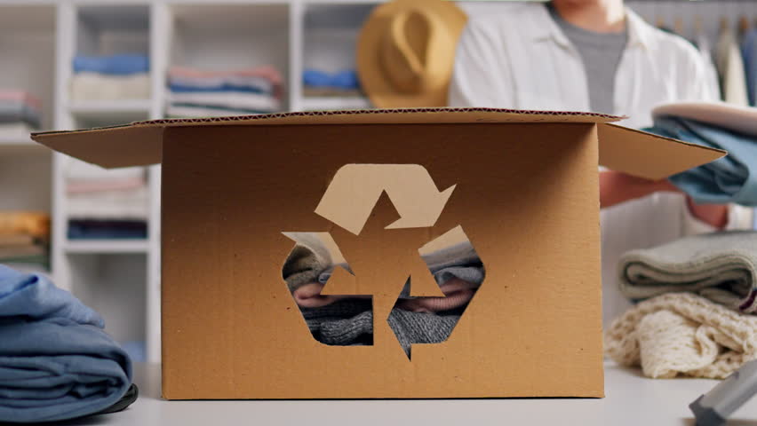 Recycling symbol sign of recyclable raw materials of clothing products, Girl sorts clothes for recycling recycling, collection of unnecessary clothes for reuse box with clothes
 | Shutterstock HD Video #1098822595