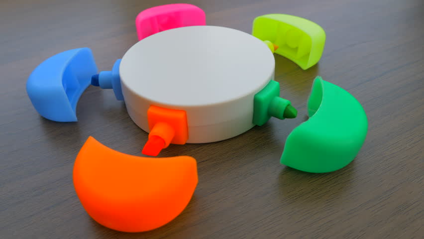 Dolly shot of five different brightly colored highlighter marker pens - yellow, orange, pink, blue, green - in one convenient round unit on a desk, each with its lid off next to the writing tip. | Shutterstock HD Video #1098824389