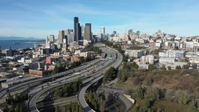 stationary aerial video view of Seattle Downtown with moving traffic on Highway, crossing central city - ferry wheel and snow covered mountains visible in the background - footage