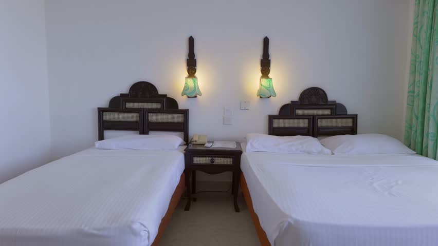 Zooming Shot Of Two Single Beds In Classic Bedroom Under Suspended Lights