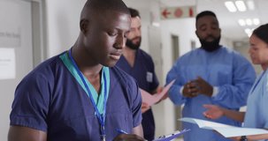 Video portrait of smiling african american male medical worker in busy hospital corridor. Hospital, medical and healthcare services.
