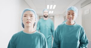 Video of four diverse surgeons in surgical caps and gowns walking in hospital corridor talking. Hospital, medical and healthcare services.