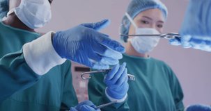 Video of diverse female surgeon and surgical assistants passing instruments during operation. Hospital, medical and healthcare services.