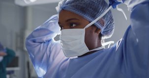 Video of african american female surgeon tying face mask in operating theatre. Hospital, medical and healthcare services.