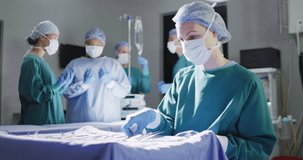 Video of smiling caucasian female surgeon checking instruments in operating theatre, copy space. Hospital, medical and healthcare services.