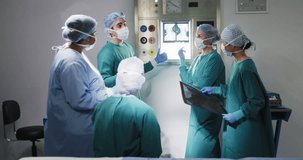 Video of diverse group of surgeons discussing x-ray in operating theatre before operation. Hospital, medical and healthcare services.
