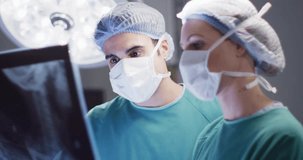 Video of caucasian male and female surgeon studying x-ray in operating theatre. Hospital, medical and healthcare services.