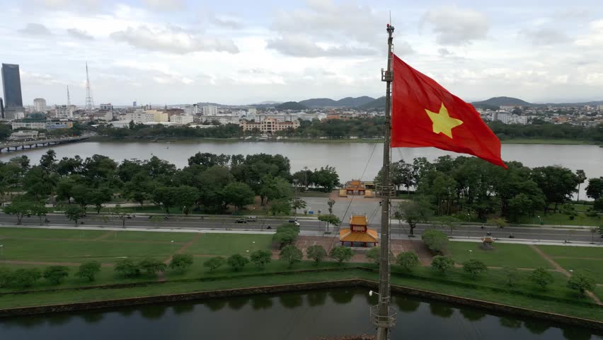 360 aerial shot around the Vietnamese flag in Hué, Vietnam on a beautiful day in lush greenery Royalty-Free Stock Footage #1098838329