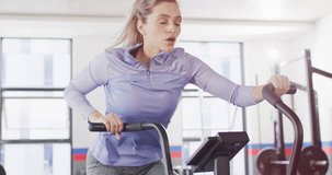 Video of determined caucasian woman on exercise bike working out at a gym. Exercise, fitness and healthy lifestyle.