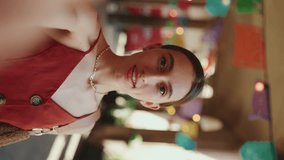 VERTICAL VIDEO: Сlose-up young woman takes a selfie, video call on the street on urban background. Smiling girl use social media, streaming service