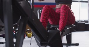 Video of determined african american woman using rowing machine working out at gym. Exercise, fitness and healthy lifestyle.