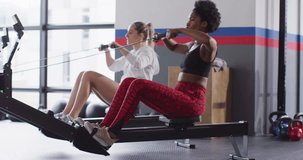 Video of two diverse, confident women on rowing machines working out at a gym. Exercise, fitness and healthy lifestyle.