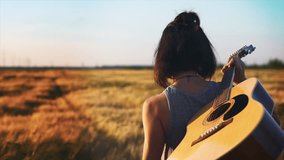 Beautiful Asian hipster woman guitar player walking on a sunny field with a acoustic. The girl in trendy sunglasses enjoy summer sunset and walking forward in countryside. Youth and creativity concept - Powered by Shutterstock - Get 15% off with code: PIKWIZARD15
