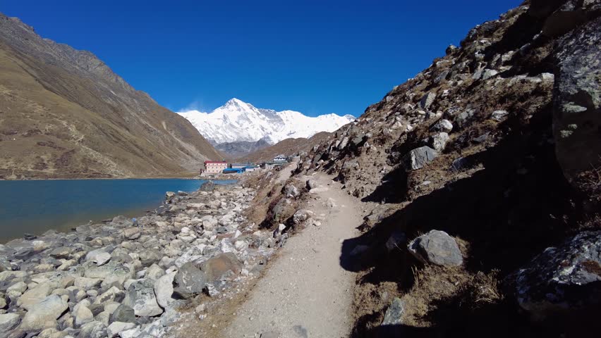 Gokyo, Nepal: Point of view of an hiker walking along the lake toward Gokyo village at 4800m with Cho Oyu peak in the Khumbu region in the Himalayas in Nepal