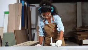 Black african american girl wearing noise canceling headphones lumberjack designing furniture to make wardrobes, window sills, blowing sawdust dust working in a furniture factory. - Powered by Shutterstock - Get 15% off with code: PIKWIZARD15