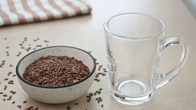 Serving flaxseed milk in glass cups with raw flax seeds in the background.
