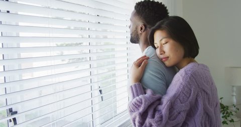 Happy diverse couple embracing and looking through window in bedroom. Spending quality time at home concept. Video Stok