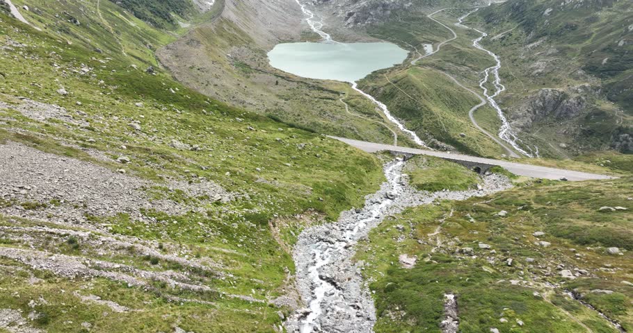 Mountain lake called the Steinsee on top of the Sustenpass in Switzerland. Aerial overhead view. Driving road, rocks, grass, moss and mountain landscape.