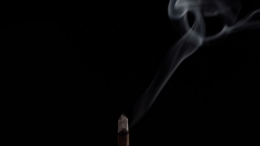 Clouds of fragrant smoke from a smoldering stick of incense for meditation, yoga and relaxation on a black background Royalty-Free Stock Footage #1098849377