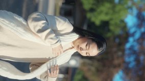 4K Vertical video : Portrait of Asian woman enjoy outdoor lifestyle travel at park in autumn morning. Attractive girl wearing knit scarf and looking beautiful ginkgo biloba tree in Tokyo city, Japan.