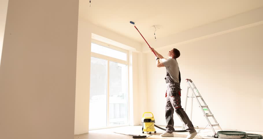 Builder manually paints the ceiling inside house and building Royalty-Free Stock Footage #1098859731