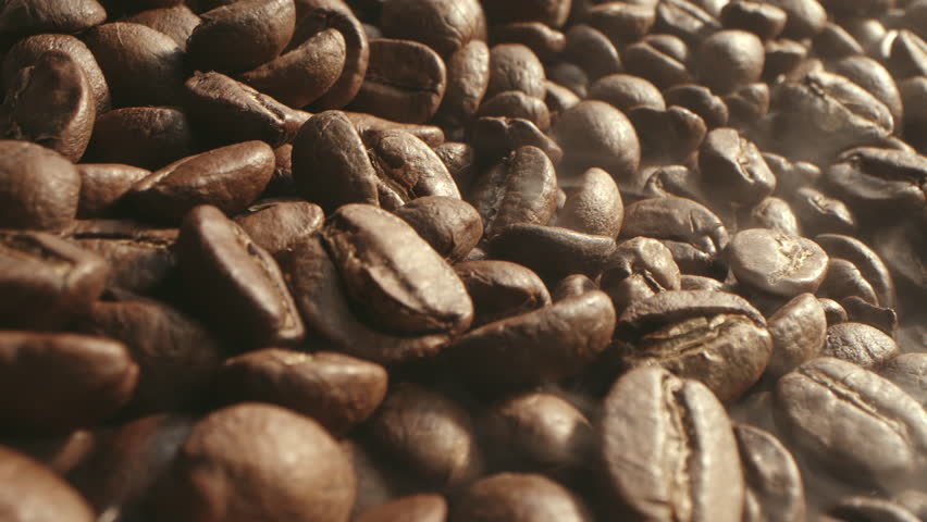 From roasting coffee beans, soft diffuse smoke emanating from roasted coffee beans, shot in a dark key smoke coming from roasting coffee beans. Aromatic coffee beans soft diffused smoke. 4K