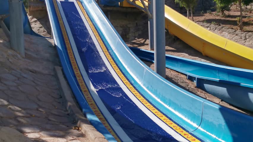 Child on water slide at aquapark. Summer holiday.
