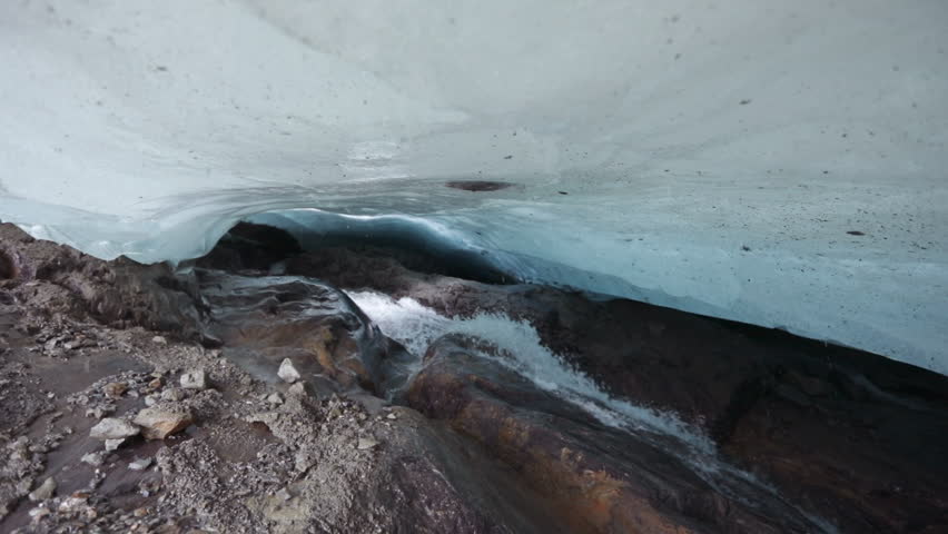Environment preservation. Glacier meltdown in summer. Inside the glacier caves. Closeup view of the white water glacier stream flowing along the rocky mountain under the glacier ice field. Royalty-Free Stock Footage #1098860447