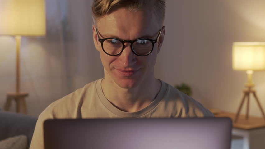 Young Caucasian Freelancer Man Working on Computer at Home at Night. Casual Concentrated Entrepreneur Developing New project While Working on Laptop Typing, Scrolling, Surfing Web, Looking at the | Shutterstock HD Video #1098861441