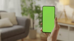 Handheld Camera: Point of View of Woman on Living Room Holding Chroma Key Green Screen Smartphone Watching Content Without Touching or Swiping. Girl Using Mobile Phone, Browsing Internet, Watching