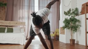 Young Beginner African American man doing gymnastics exercise on floor in living room. Attractive handsome sport male spend leisure activity time to workout for healthcare by follow online instruction