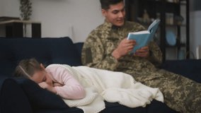 Loving military father reading book to little daughter falling asleep on couch - Powered by Shutterstock - Get 15% off with code: PIKWIZARD15