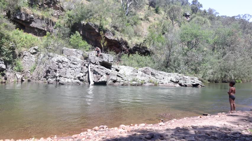 A father and son swim in a river in a remote secluded campsite in the Australian bush.